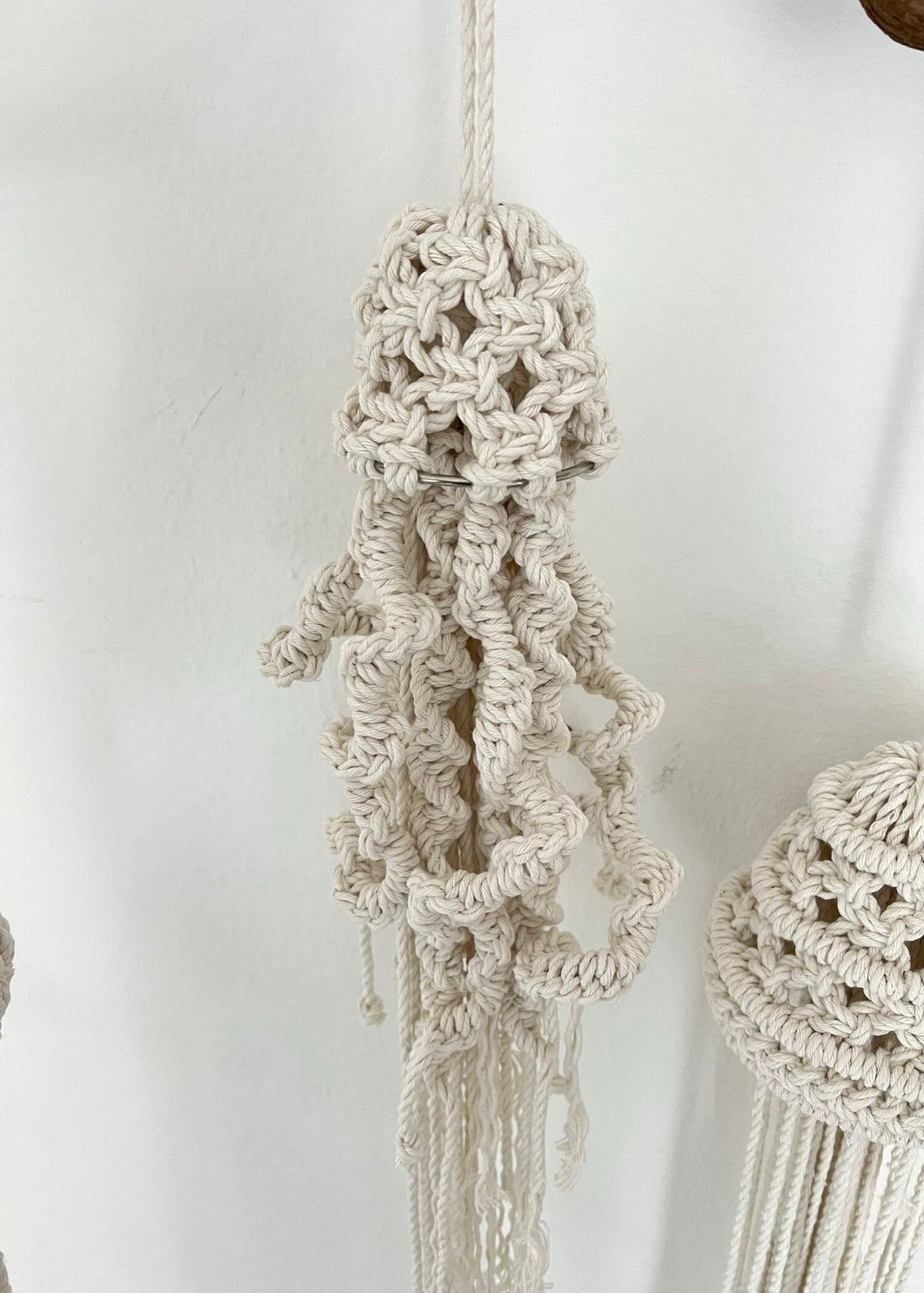 Macrame jellyfish with intricate patterns on a plain background