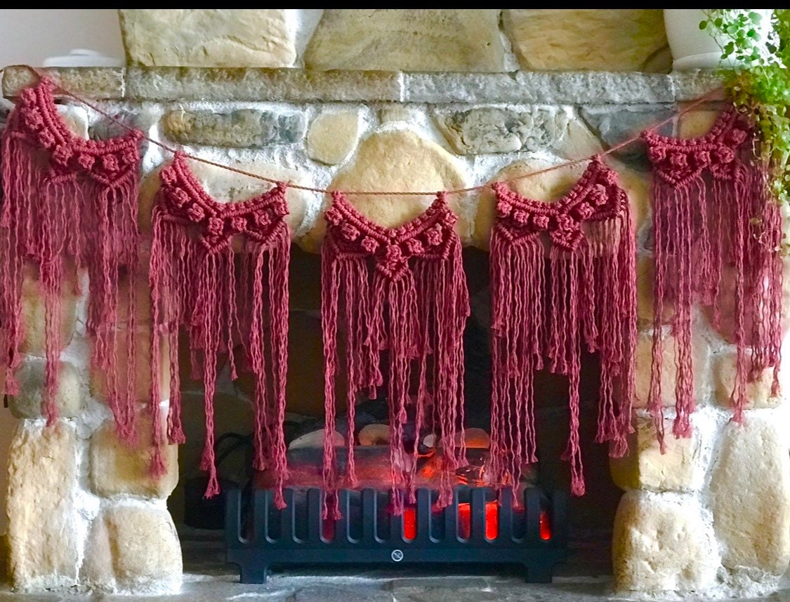 Macrame pink garland hanging above a stone fireplace.