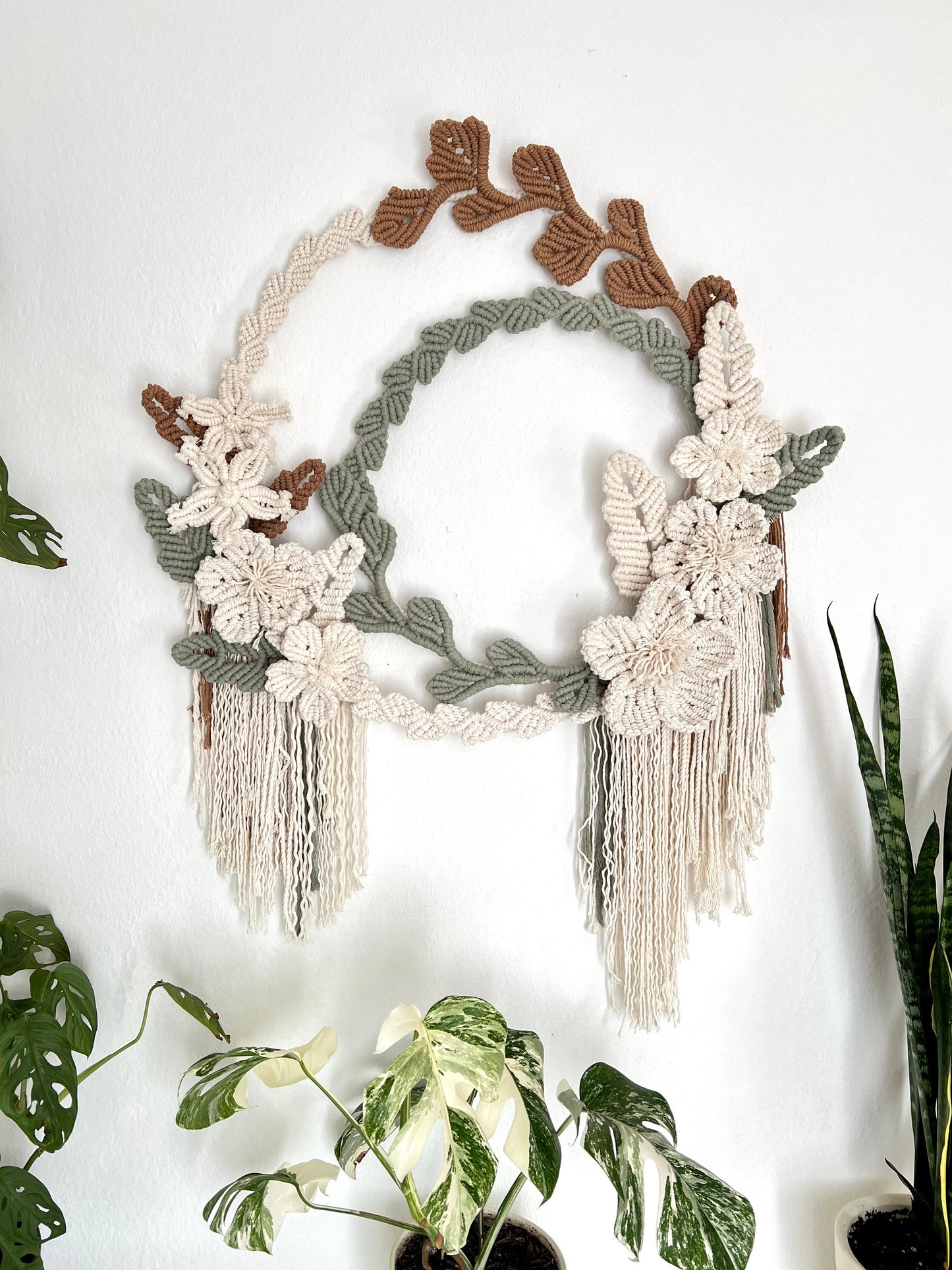 Decorative wall hanging with floral elements and tassels on a white background