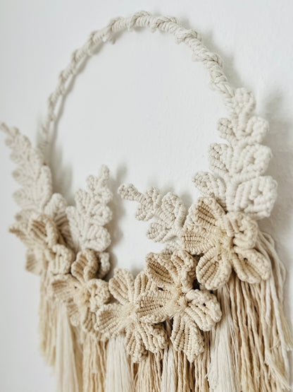 Macrame wall hanging with floral patterns and tassels on a white background