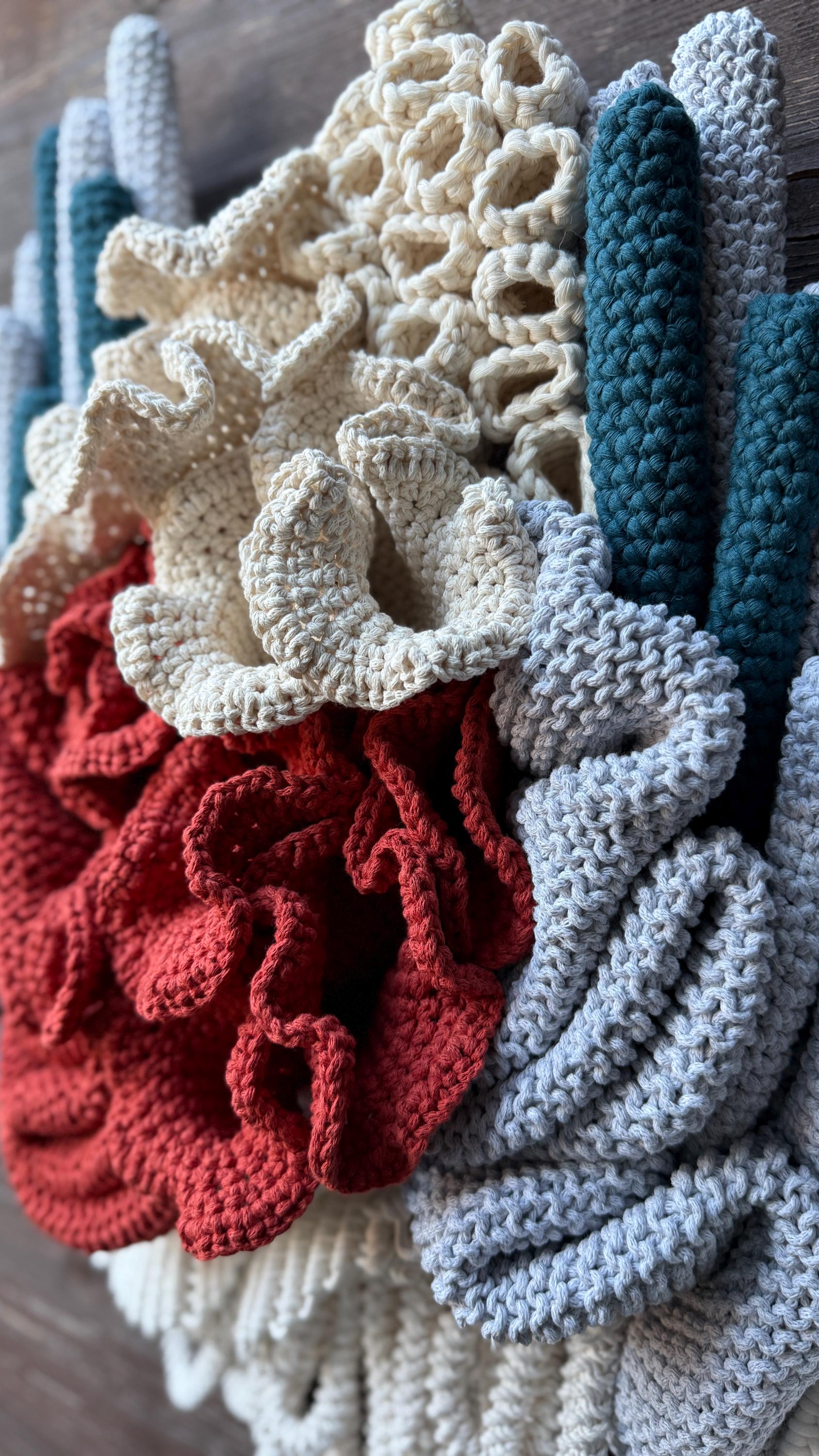 Colorful crocheted flowers of coral reef  in red, white, blue, and gray on a wooden surface.