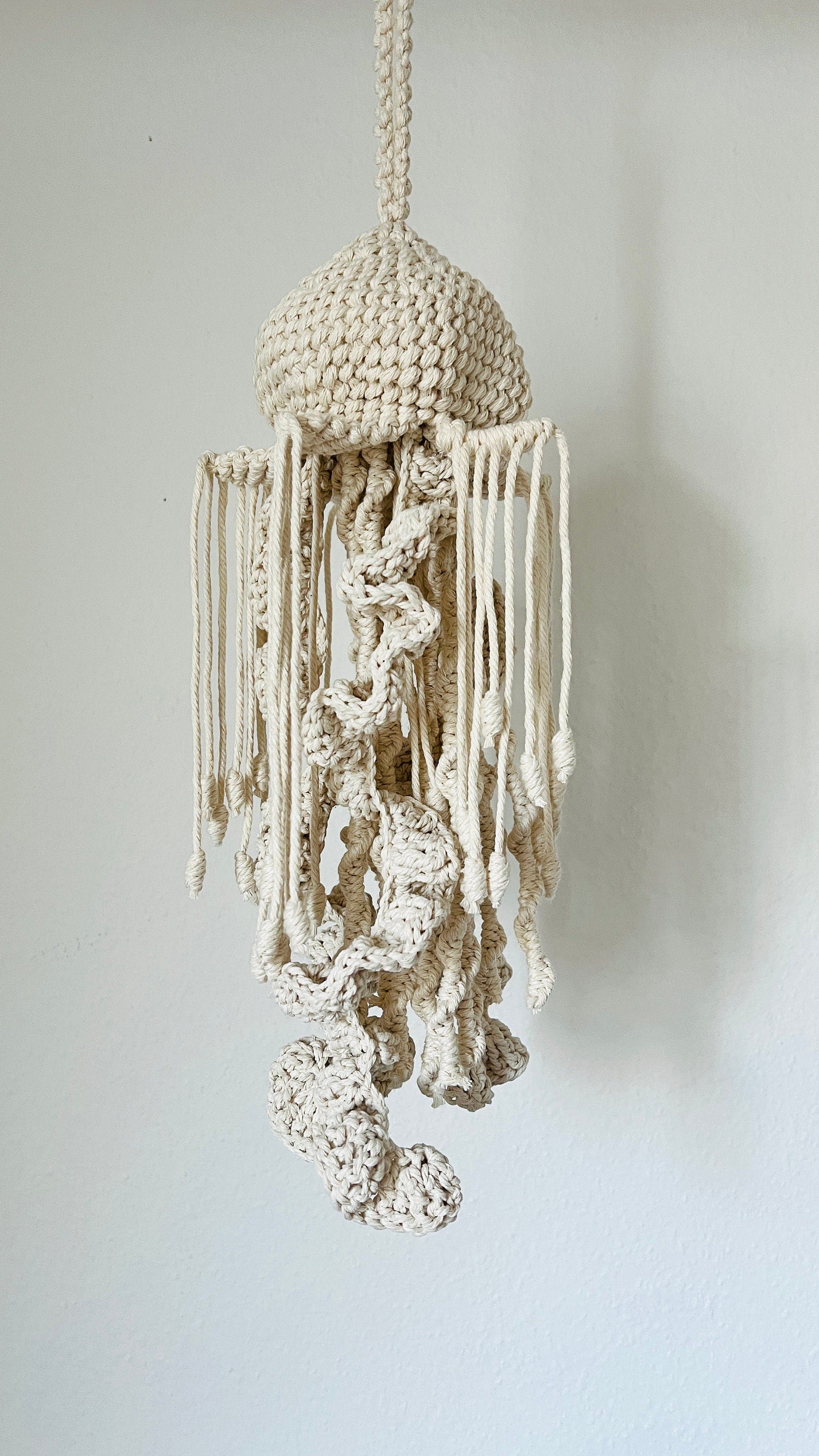 Macrame jellyfish hanging decoration on a plain background