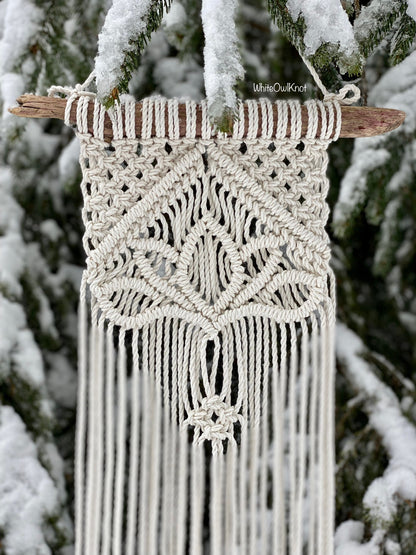 Macrame wall hanging with intricate patterns against a snowy tree background