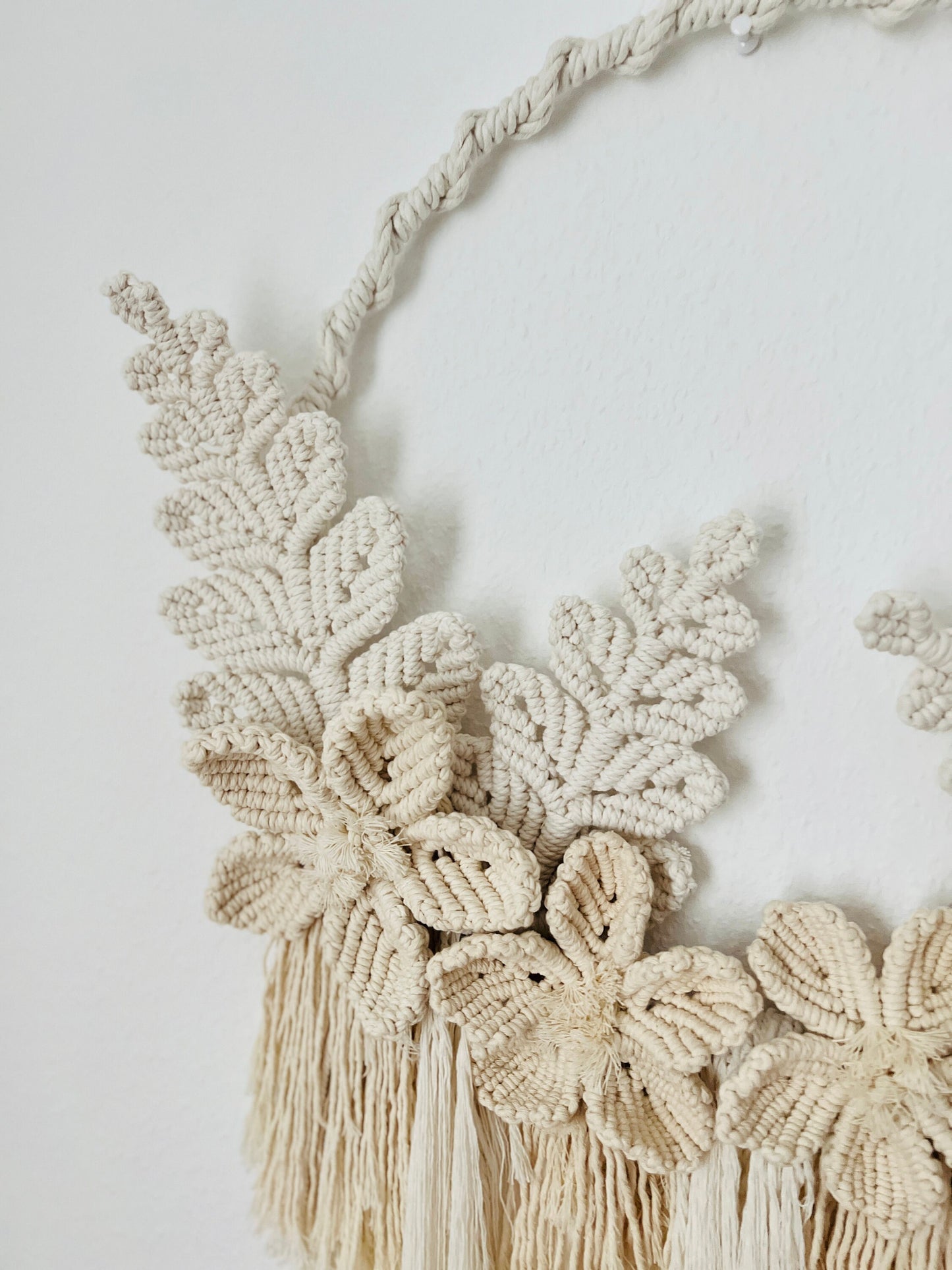 Macrame wall hanging with floral patterns and tassels on a plain background