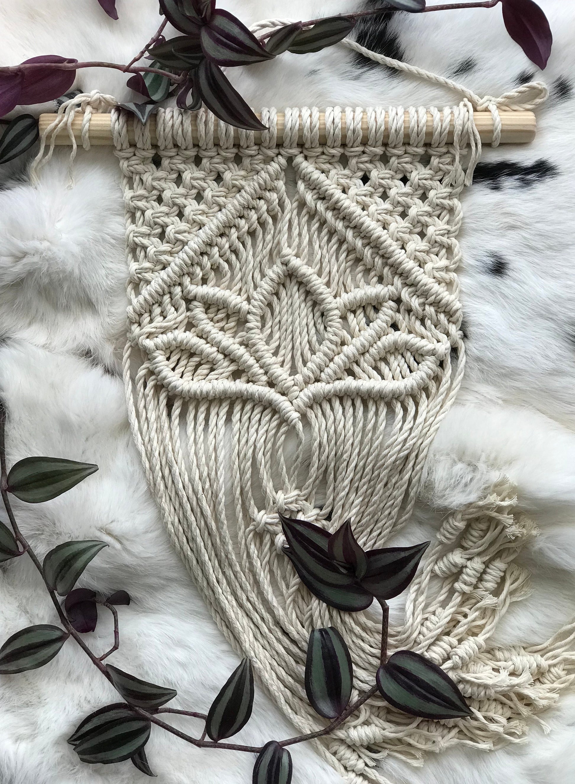 Macrame wall hanging with leaf pattern on a textured surface