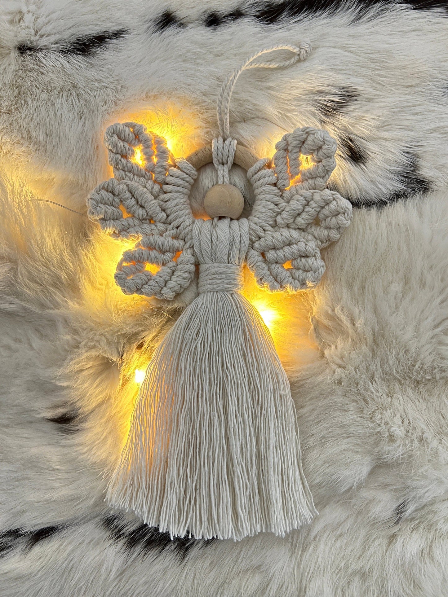 Decorative angel ornament with tassel on a fur surface