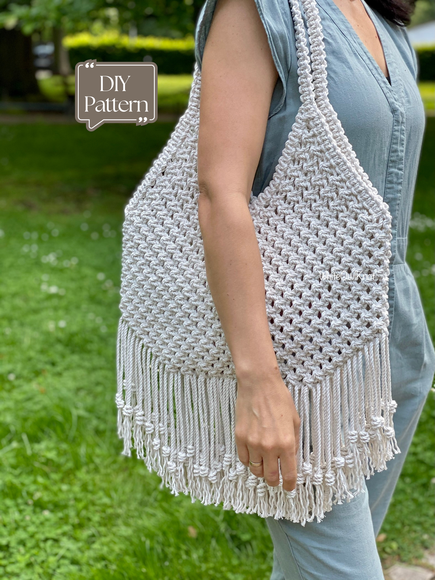 Person holding a woven macrame bag with fringe in an outdoor setting