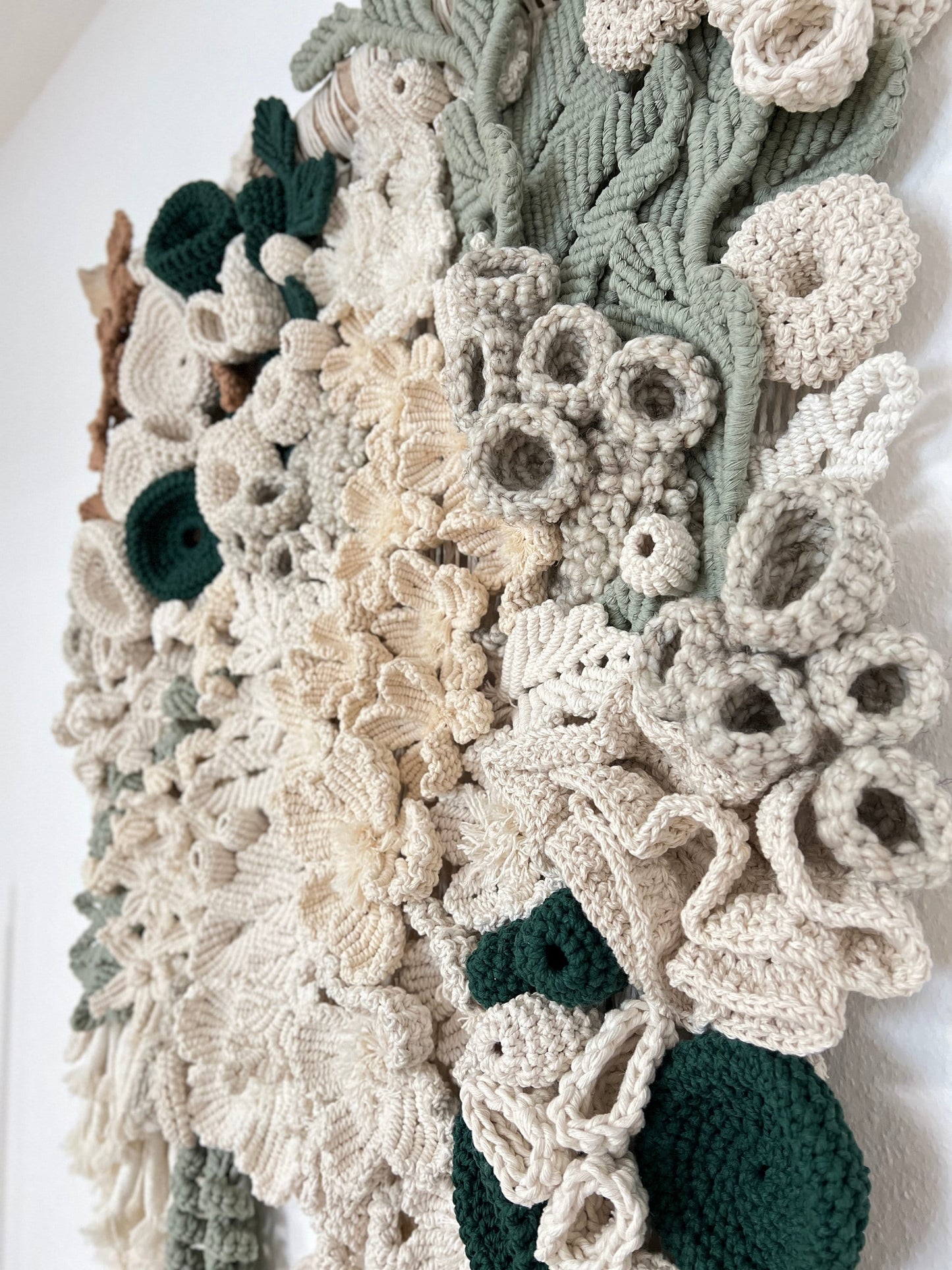 Crocheted floral fiber Art tapestry with green and beige colors on a white background
