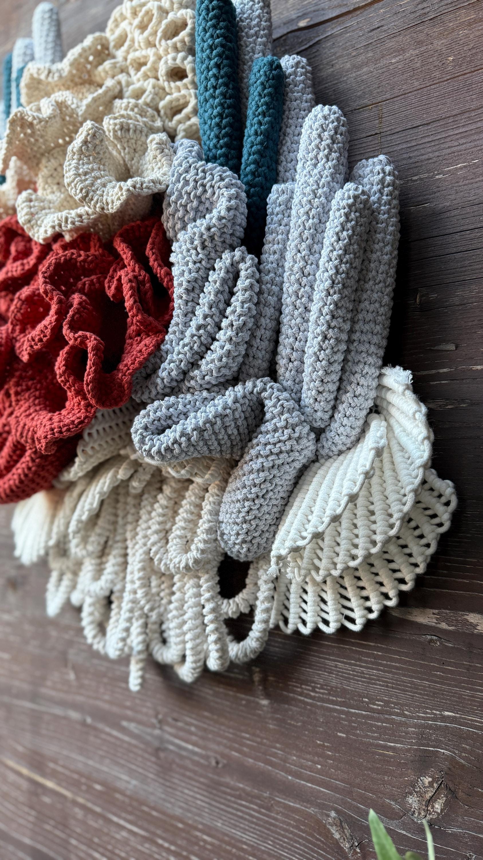Set of knitted, macrame coral reef details in various colors on a wooden surface.