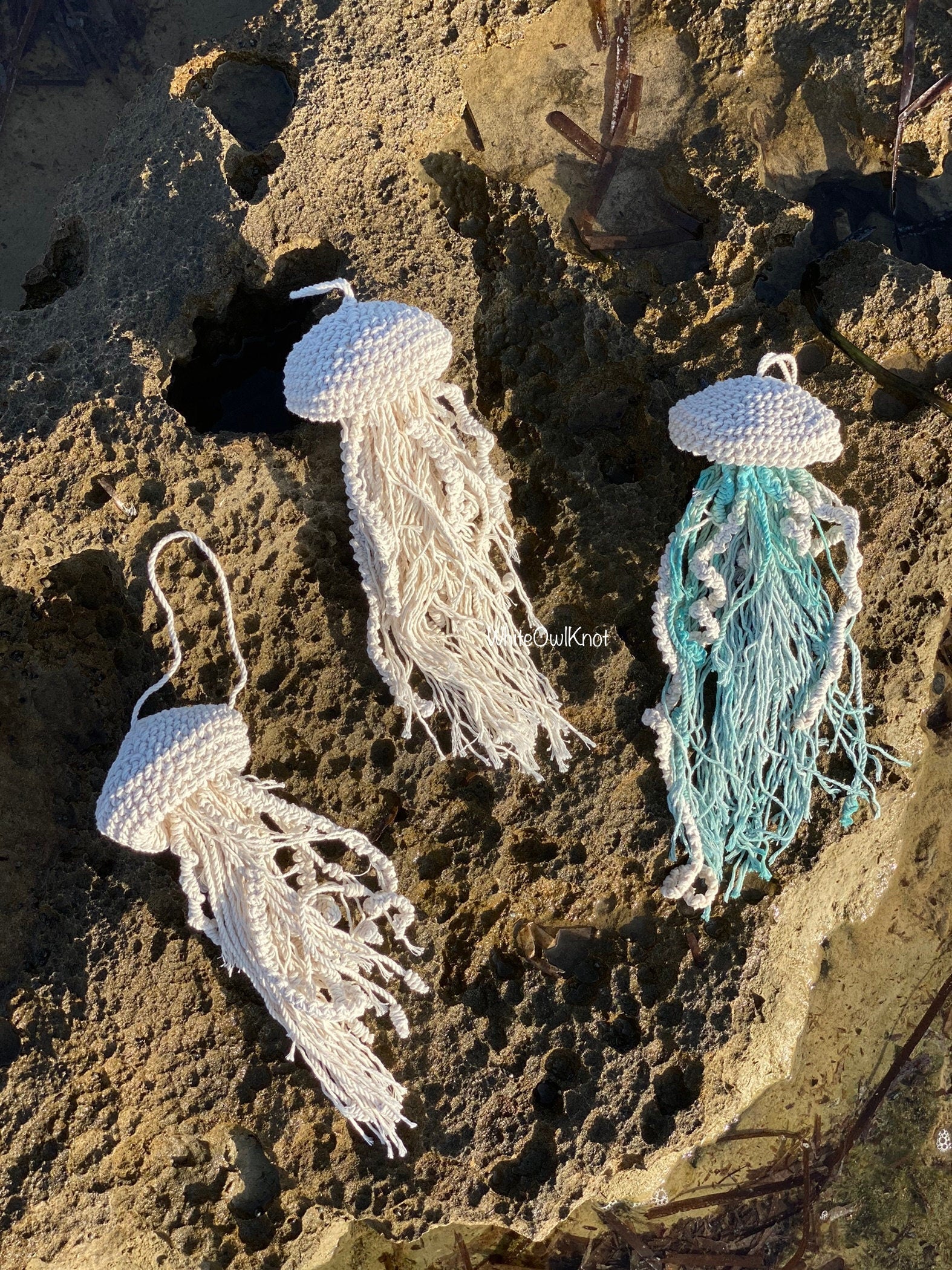 Three knotted macrame jellyfish on a textured surface