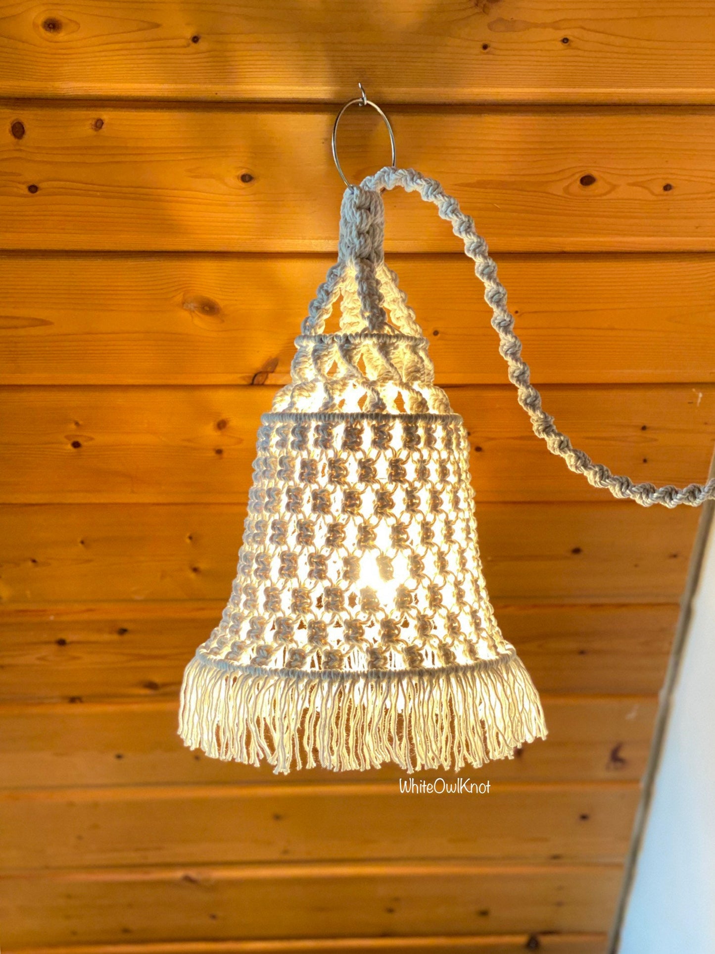 Hanging light fixture with fringes against a wooden wall