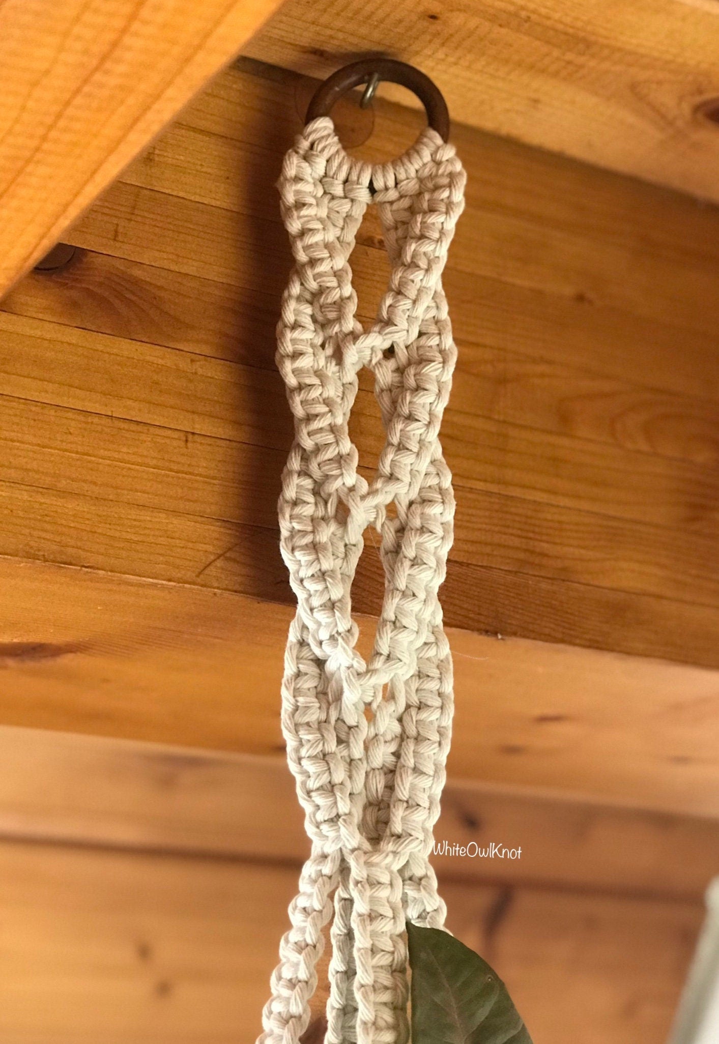 Upper part of Macrame plant hanger hanging from a wooden ceiling