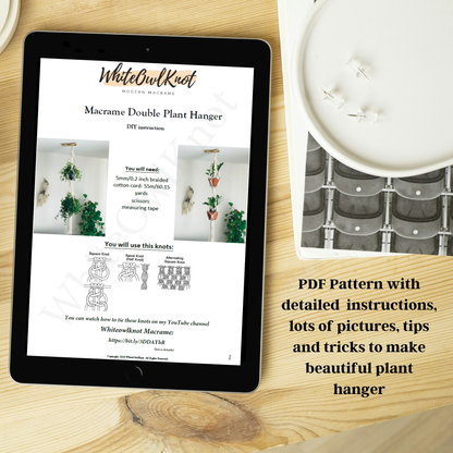 Tablet displaying a PDF pattern for a macrame double plant hanger on a wooden surface with a candle.