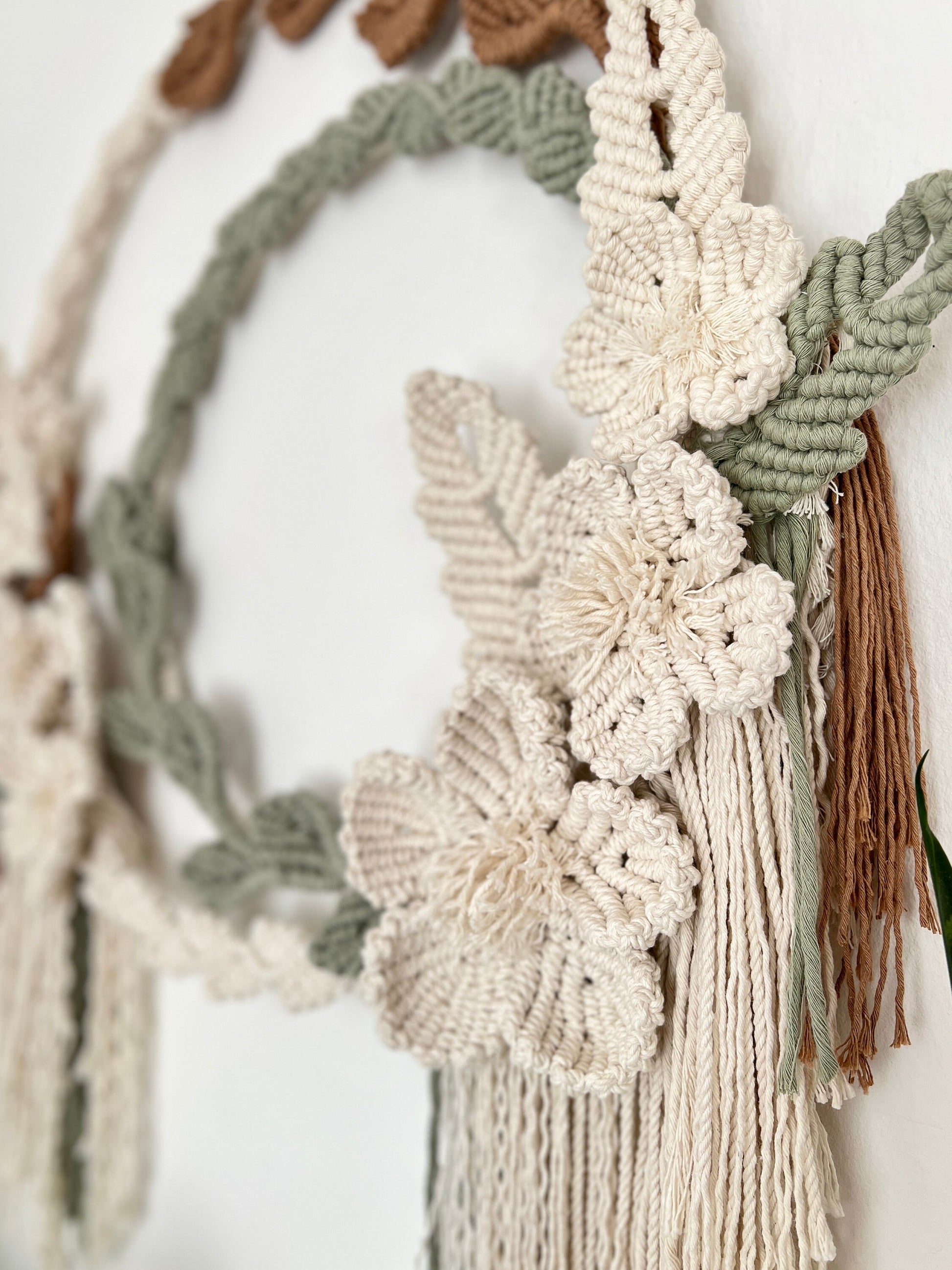 Macrame wall hanging with floral patterns and tassels on a white background