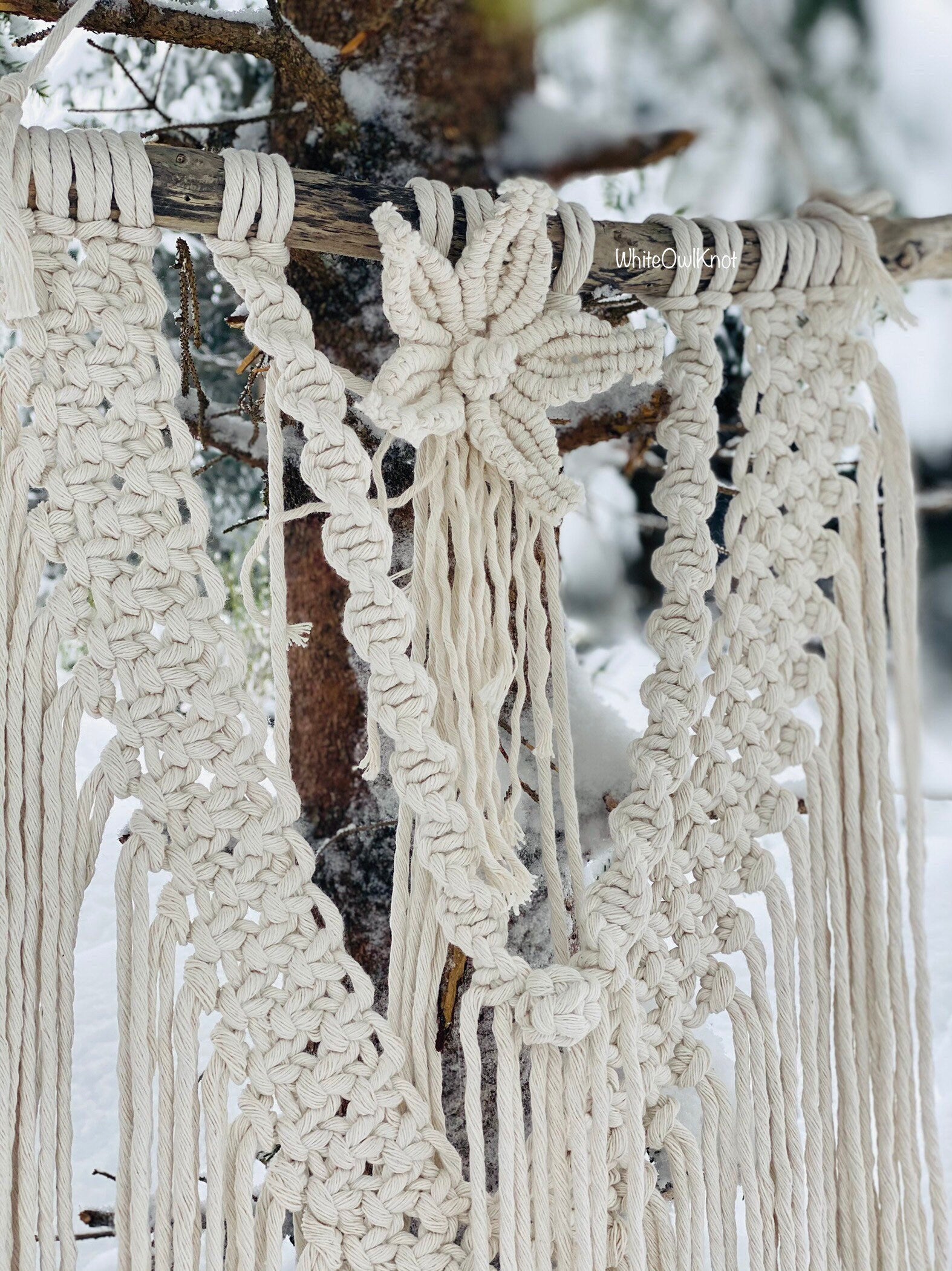 Macrame wall hanging with floral design against a snowy background