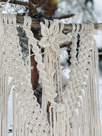 Macrame wall hanging with floral design against a snowy background