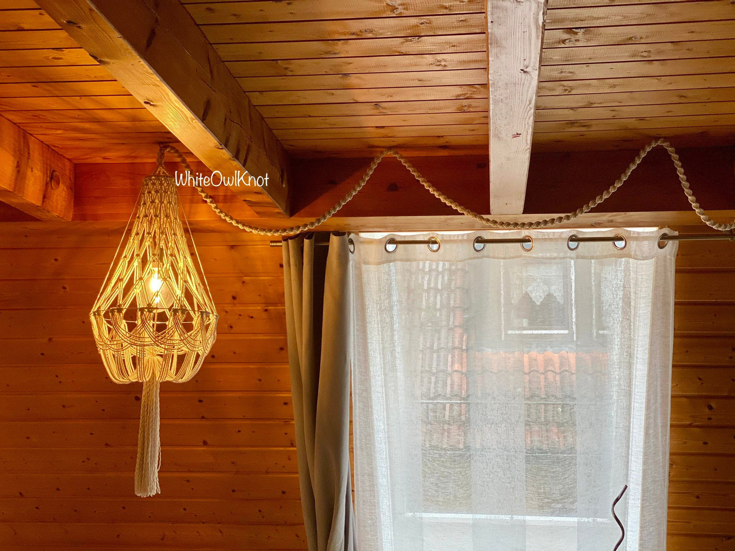 Woven light fixture hanging above a curtain in a wooden interior setting.