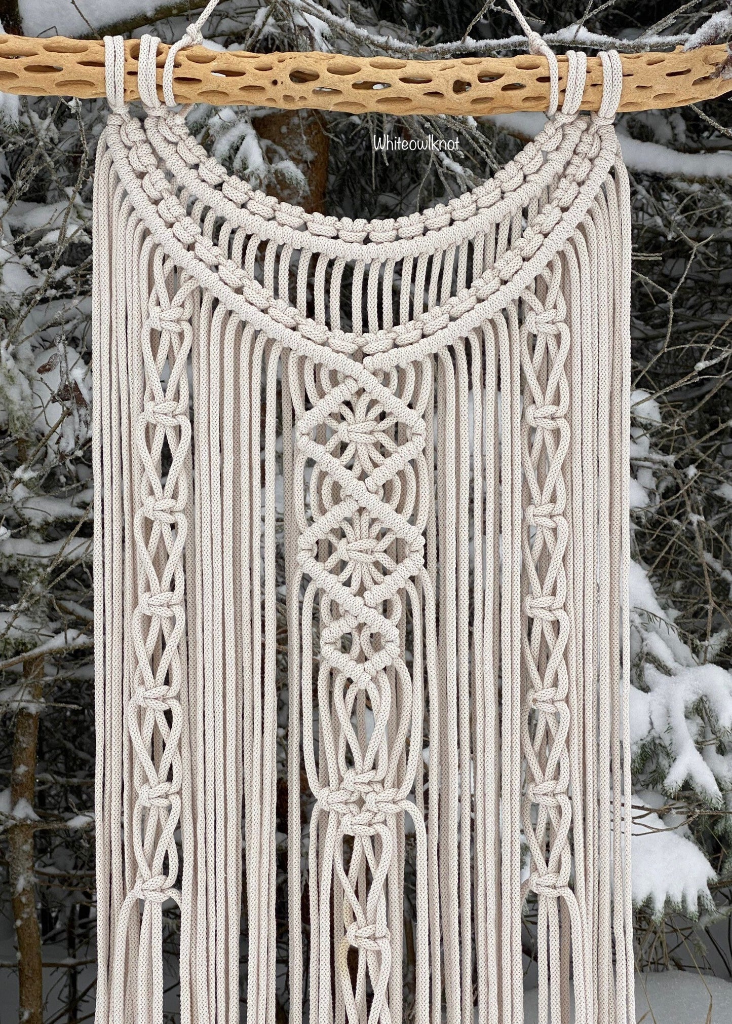 Macrame wall hanging against a snowy forest background