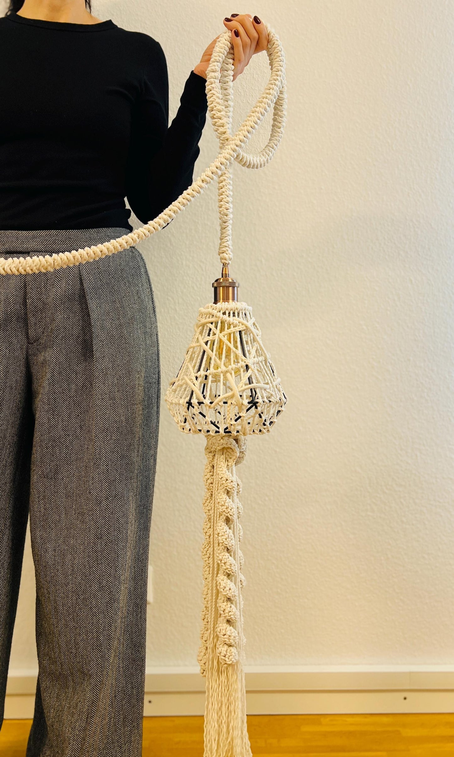 Person holding macrame shandelier against a plain background