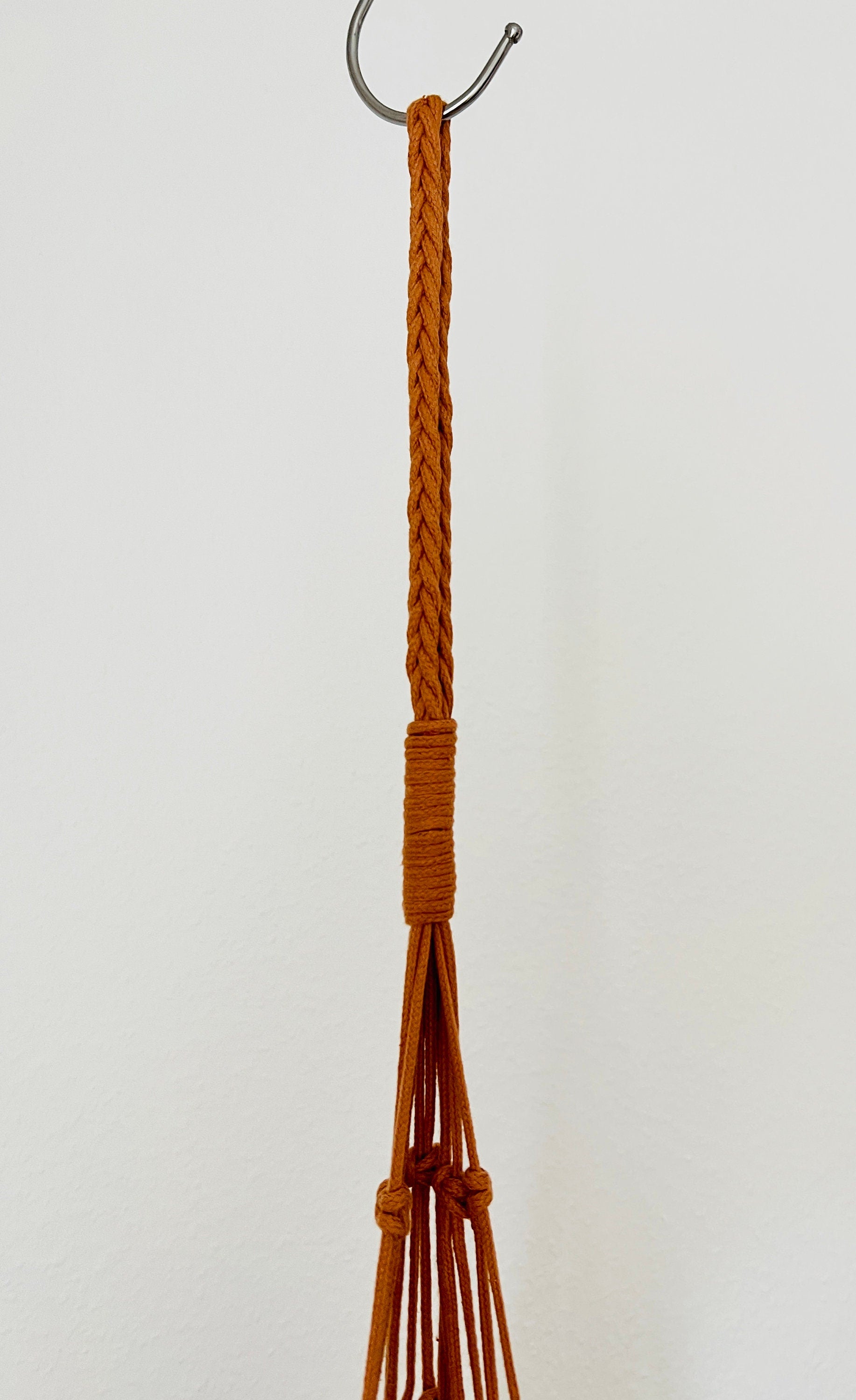 Brown braided loop on metal ring for macrame plant hanger on a white background