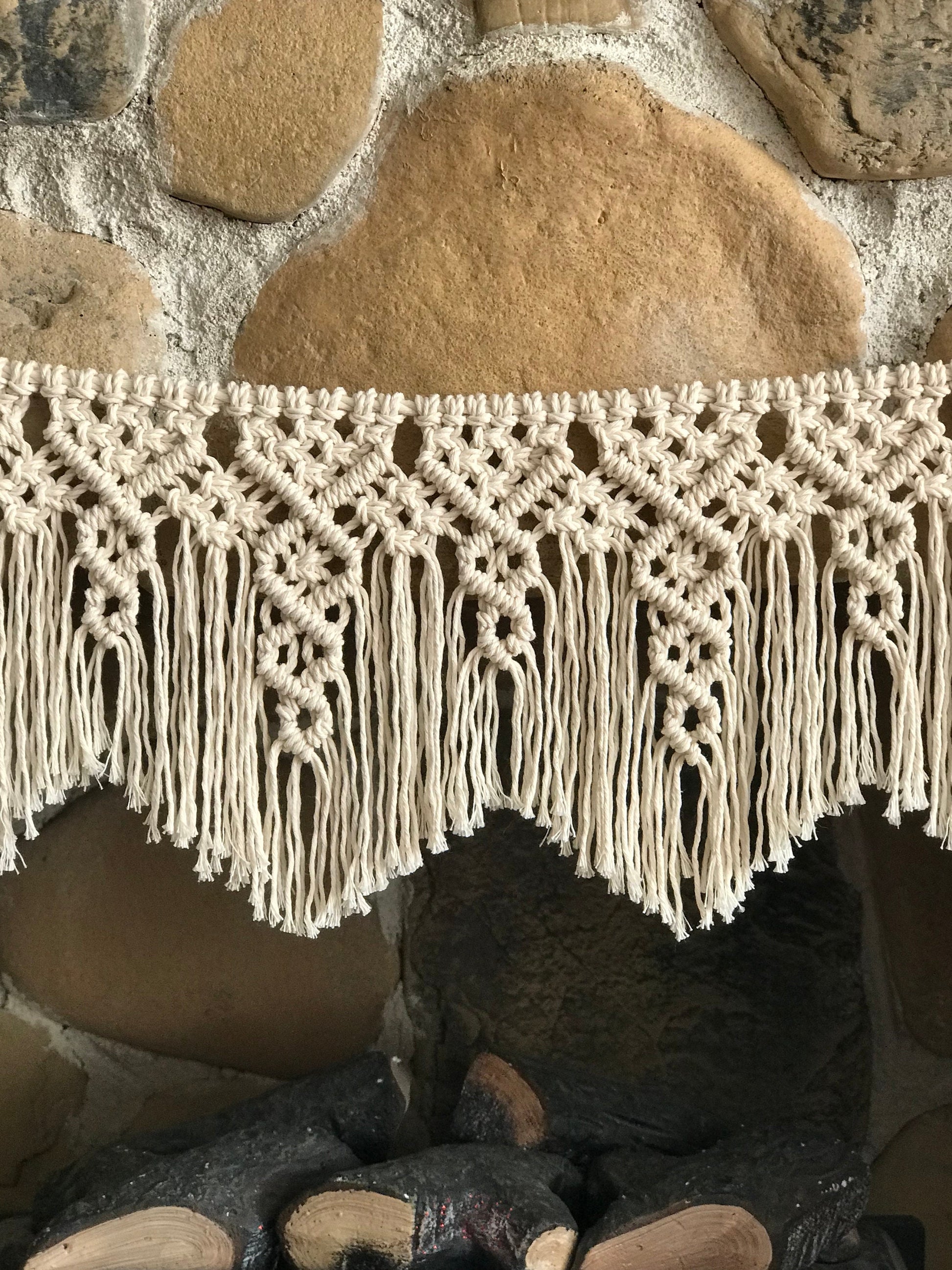 Close-up of a macrame garland's fringe against a stone wall background