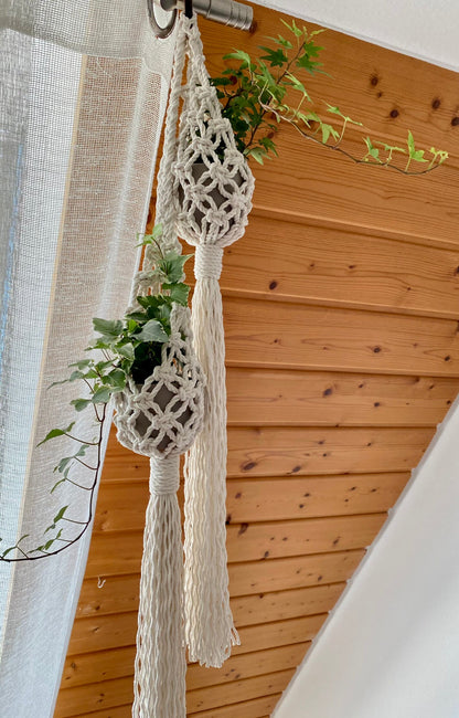 Macrame plant hanger with a plant against a wooden wall.