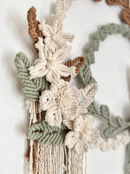 Macrame wall hanging with floral patterns on a white background