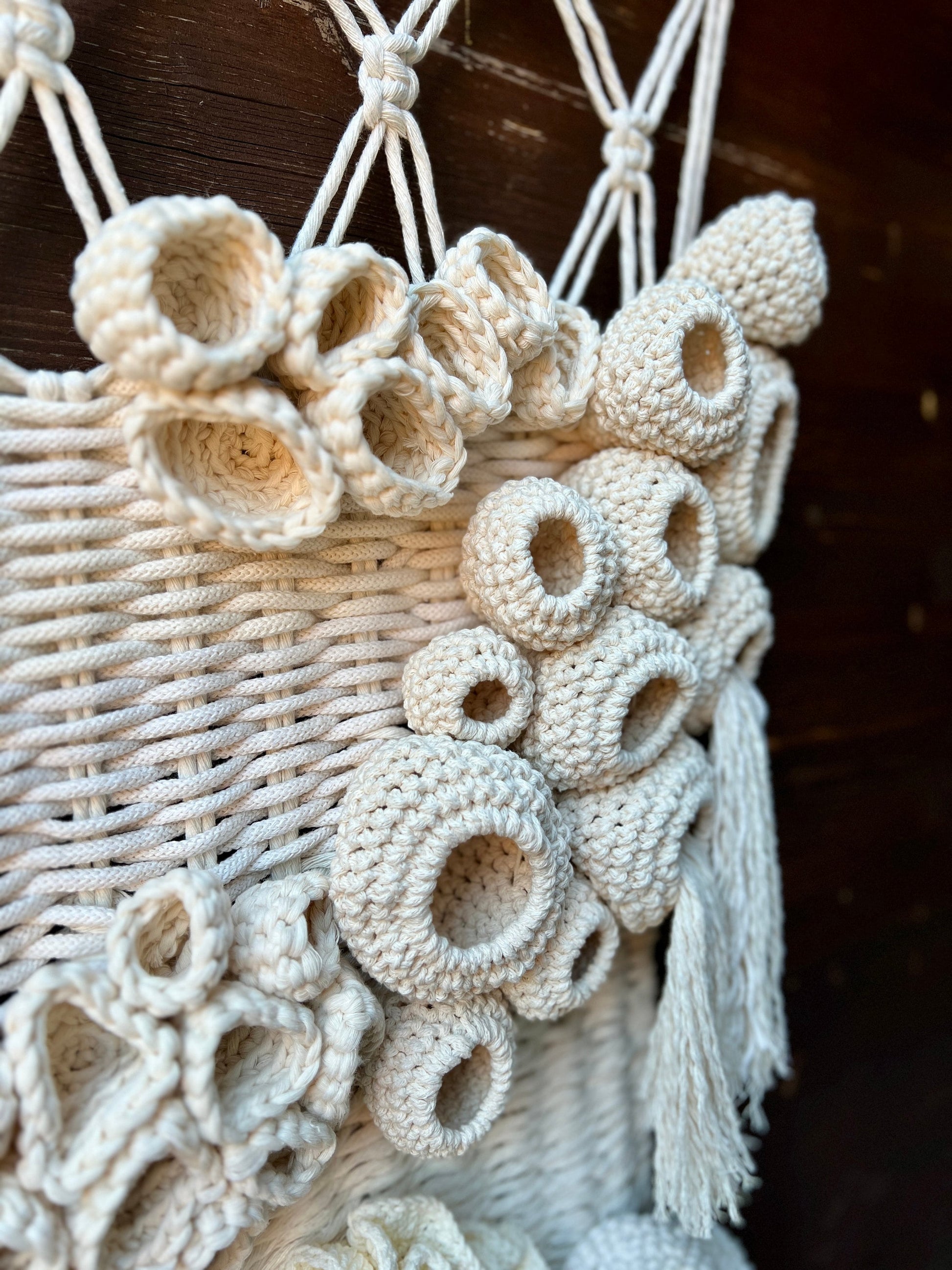 Macrame wall hanging with circular patterns and tassels on a dark background