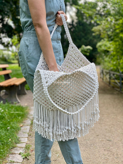 Woman holding a macrame bag outdoors with greenery in the background