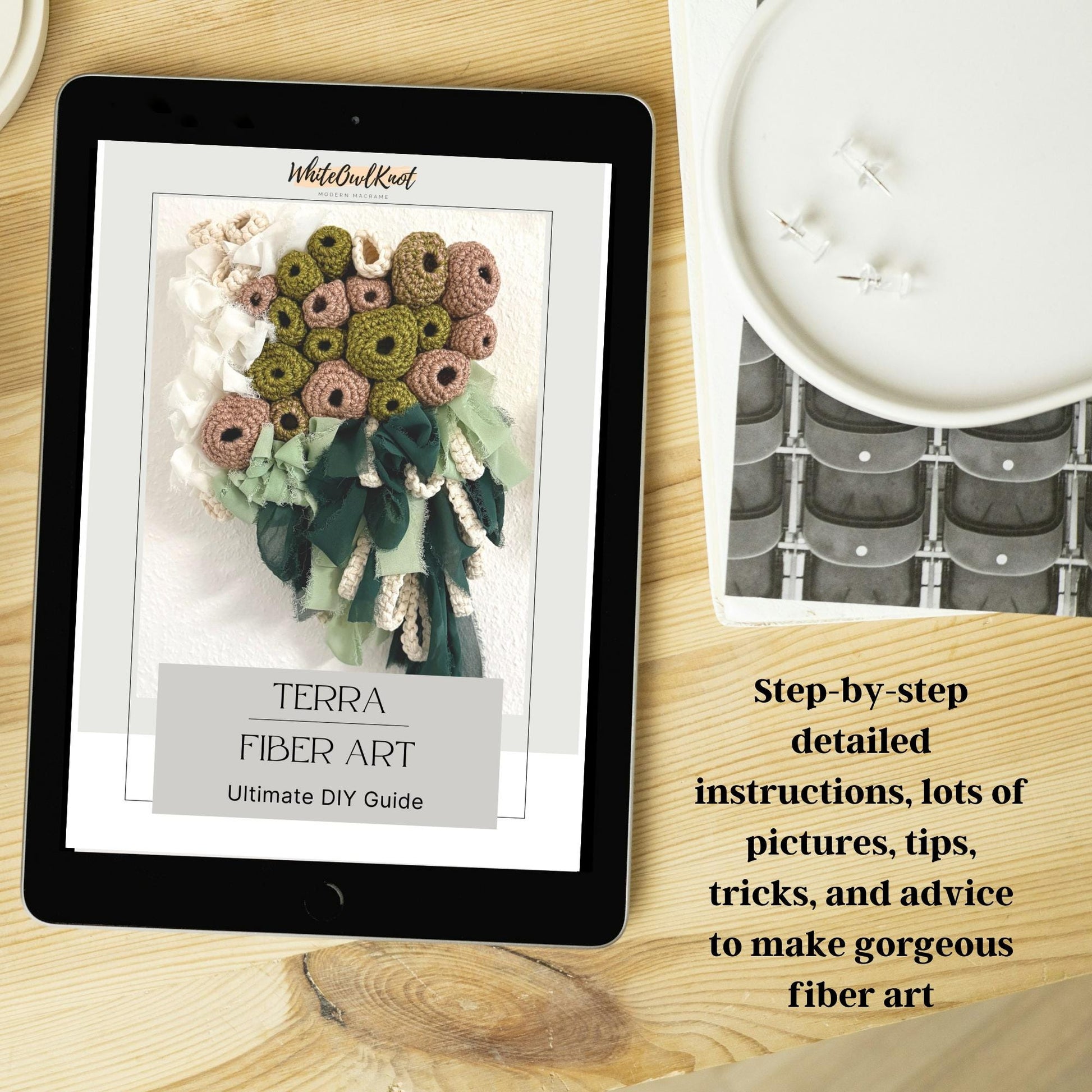 Tablet displaying a fiber art guide on a wooden surface with a candle and decorative item.