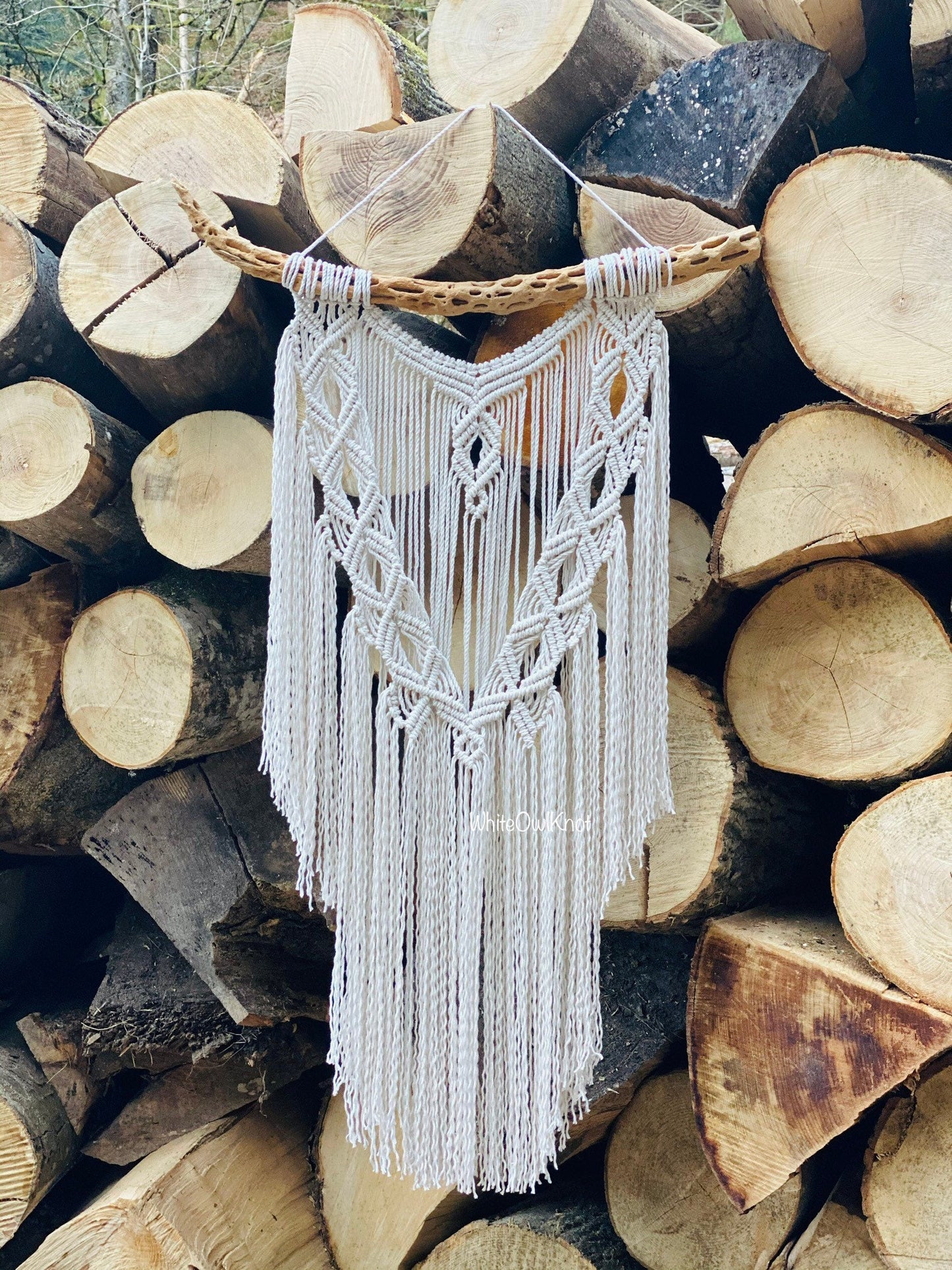 Macrame wall hanging on a stack of wooden logs