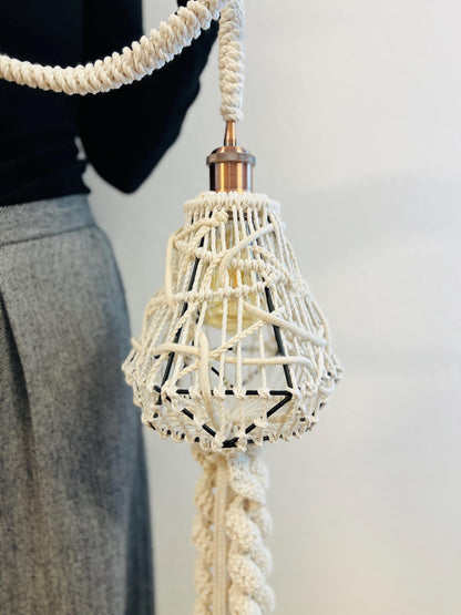 Decorative light pendant with macrame design on a plain background