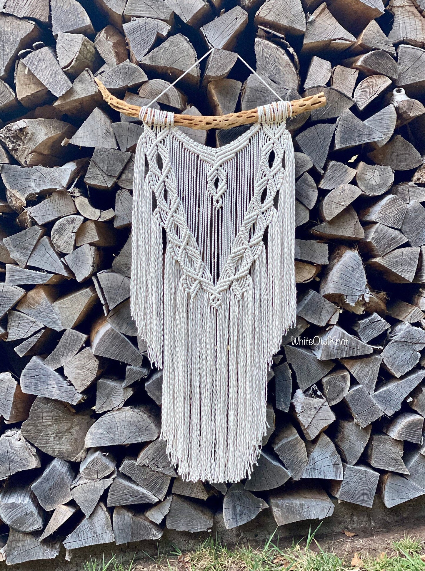 Macrame wall hanging against a background of stacked firewood