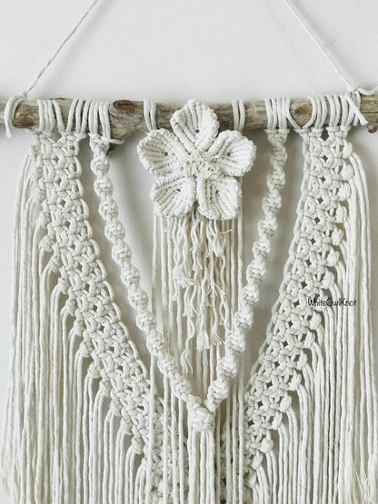 Macrame wall hanging with a butterfly ornament on a white background