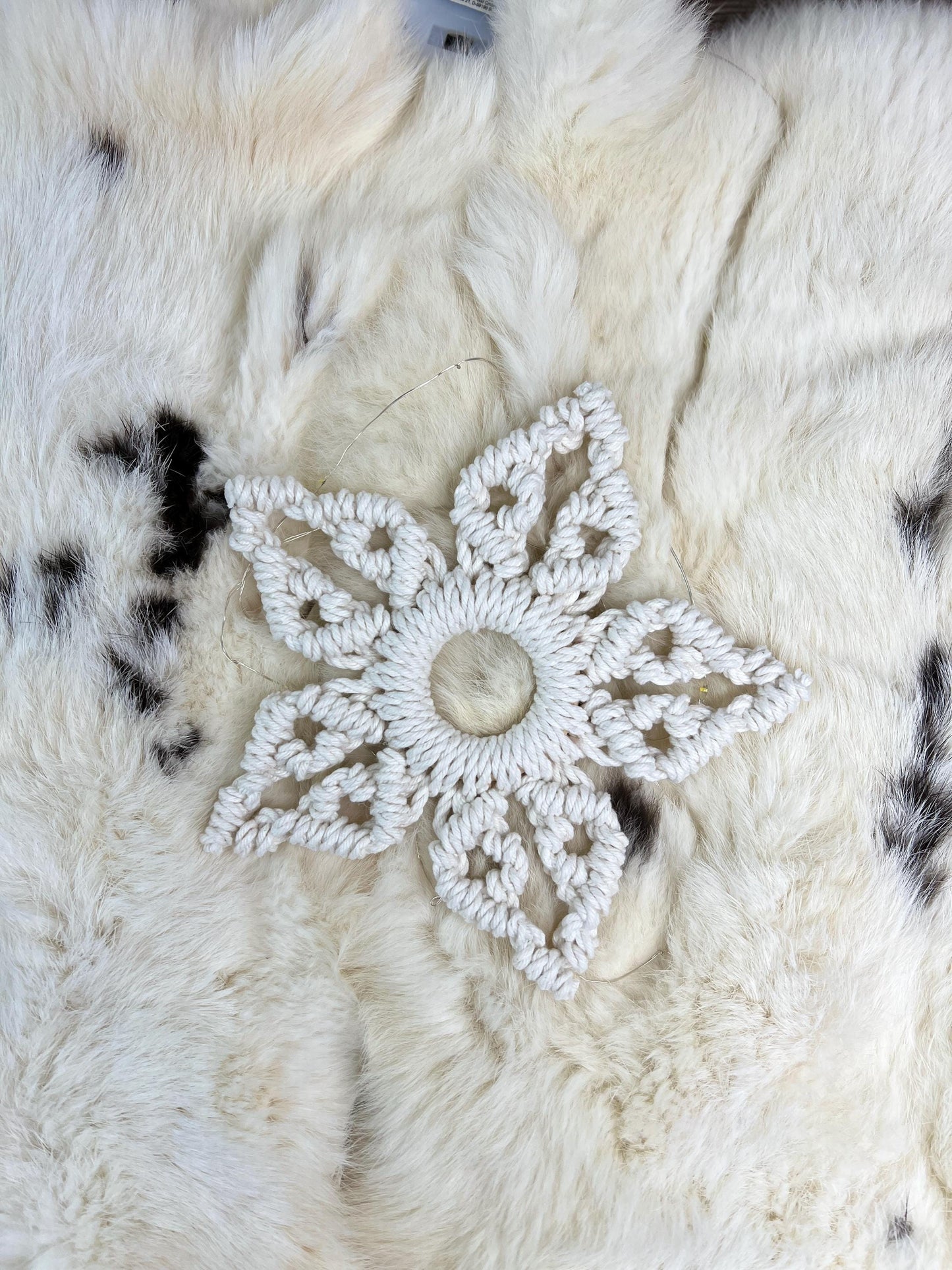 White macrame snowflake  on a textured white surface