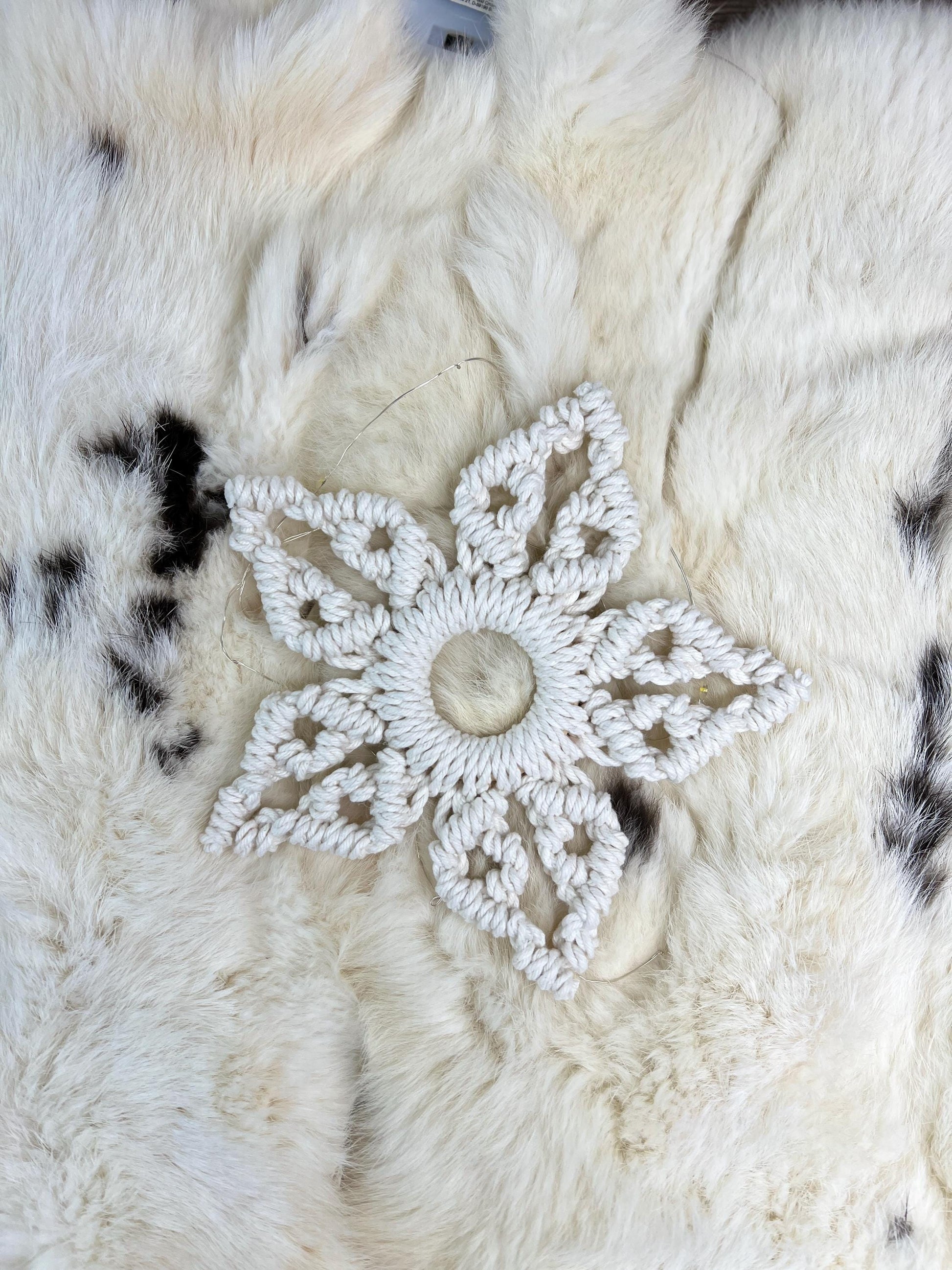 White macrame snowflake  on a textured white surface