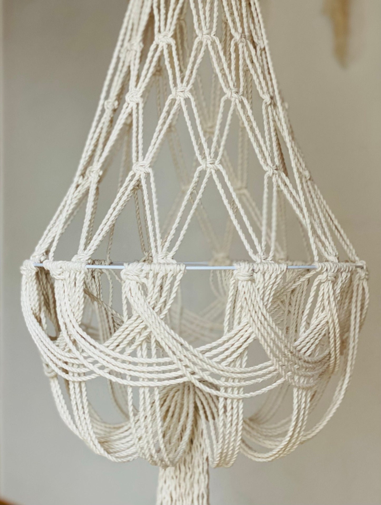 Macrame chandelier made of white rope against a neutral background