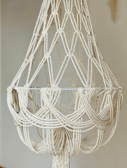 Macrame chandelier made of white rope against a neutral background