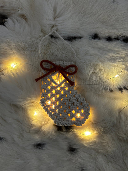 Decorative macrame Christmas Stocking with lights on a fluffy white surface
