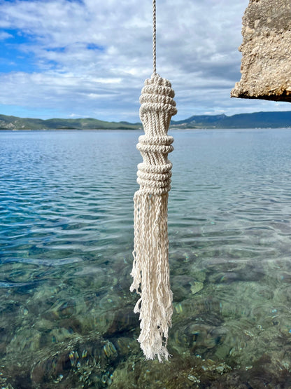 Macrame tassel hanging over a body of water with mountains in the background