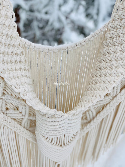 Close-up of a macrame wall hanging with a blurred natural background