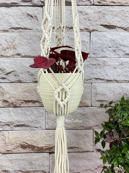 Macrame plant hanger with a plant against a stone wall background