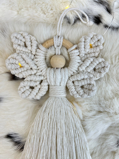 Macrame christmas angel ornament with wooden center on a fluffy white background