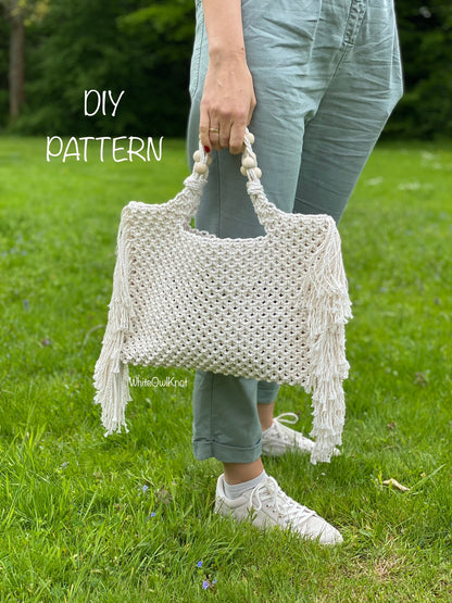 Person holding a white macrame bag with fringe on grass