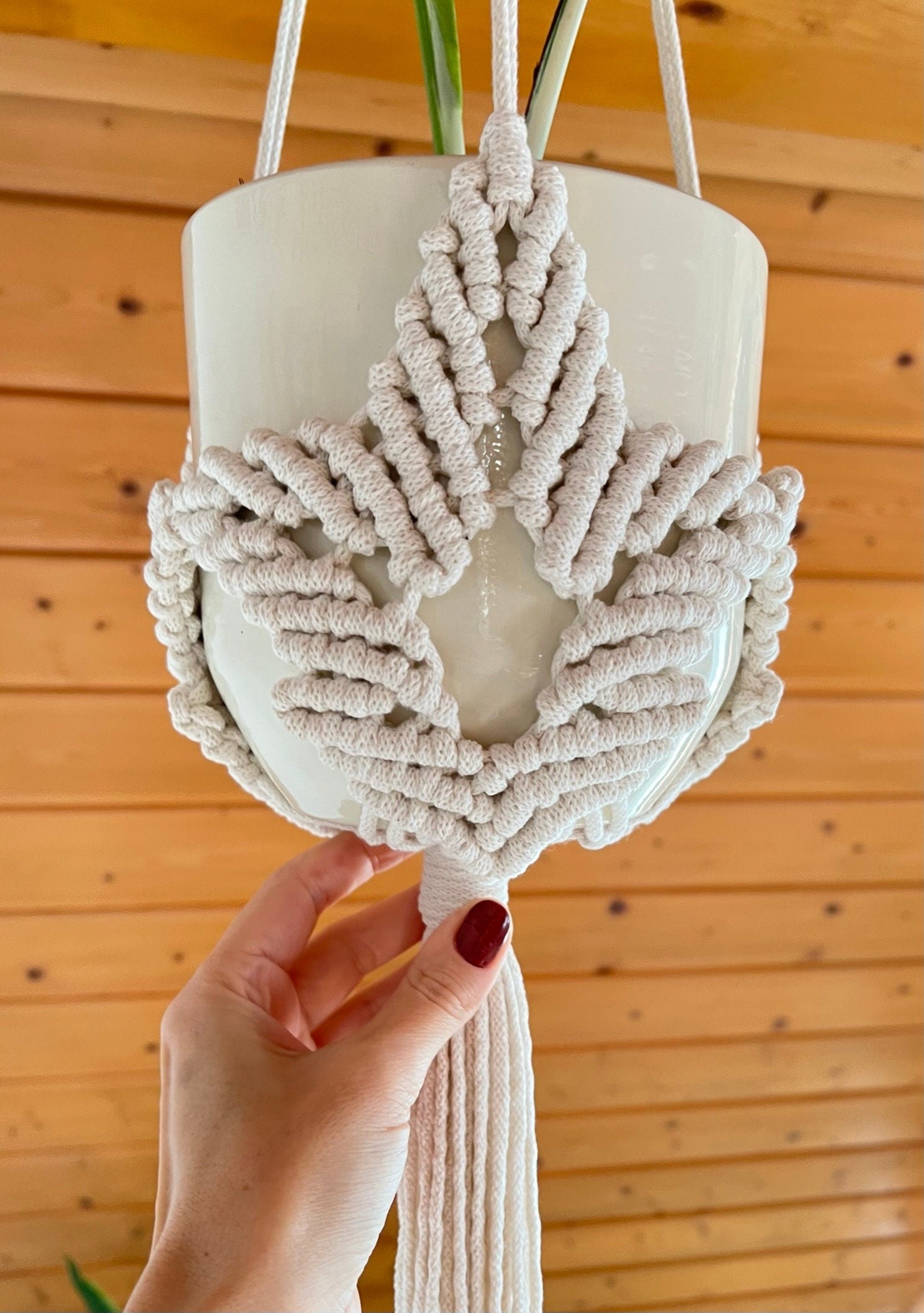 Macrame plant hanger with leaf motif on a wooden background