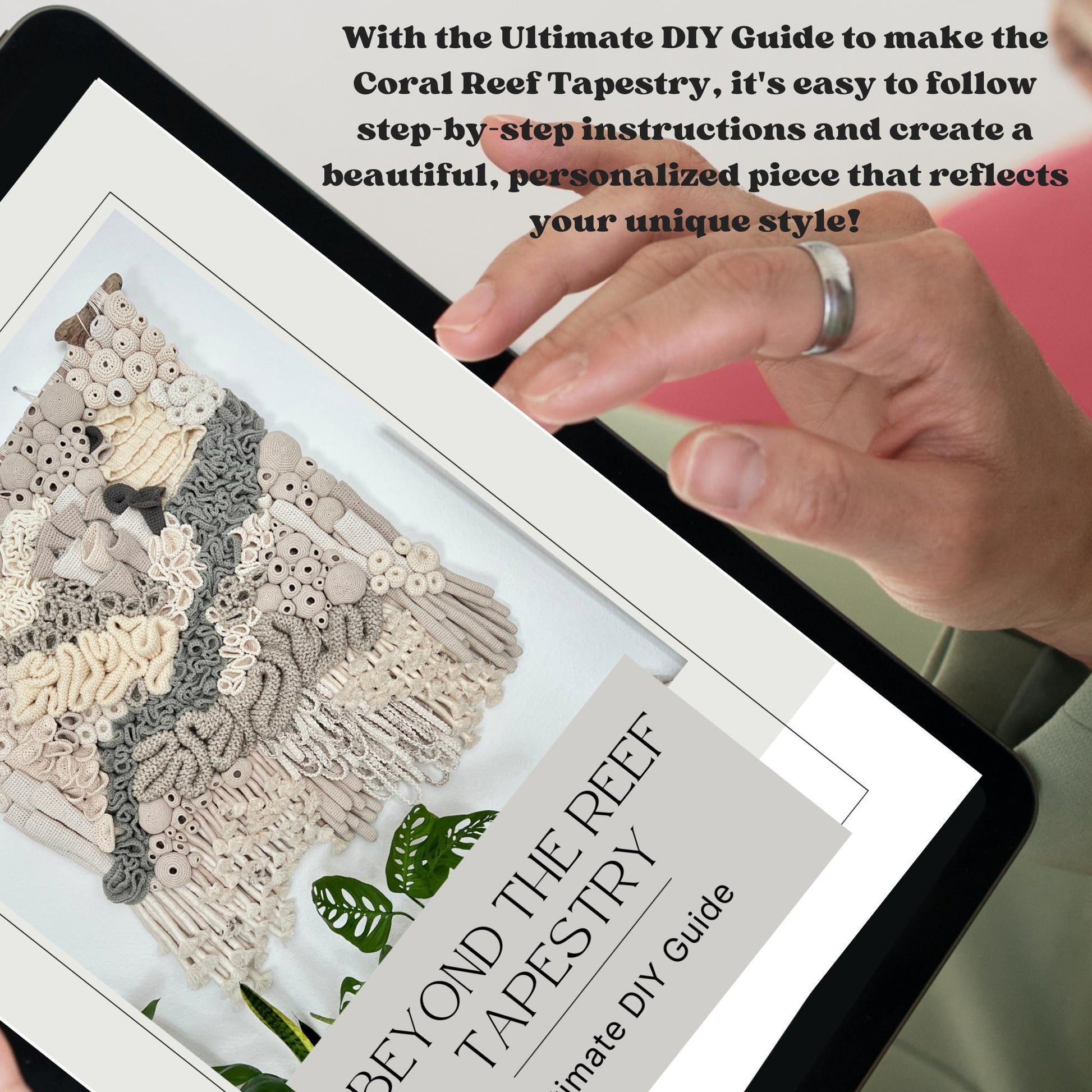 Hand holding a tablet displaying a coral reef tapestry design with text about a DIY guide.