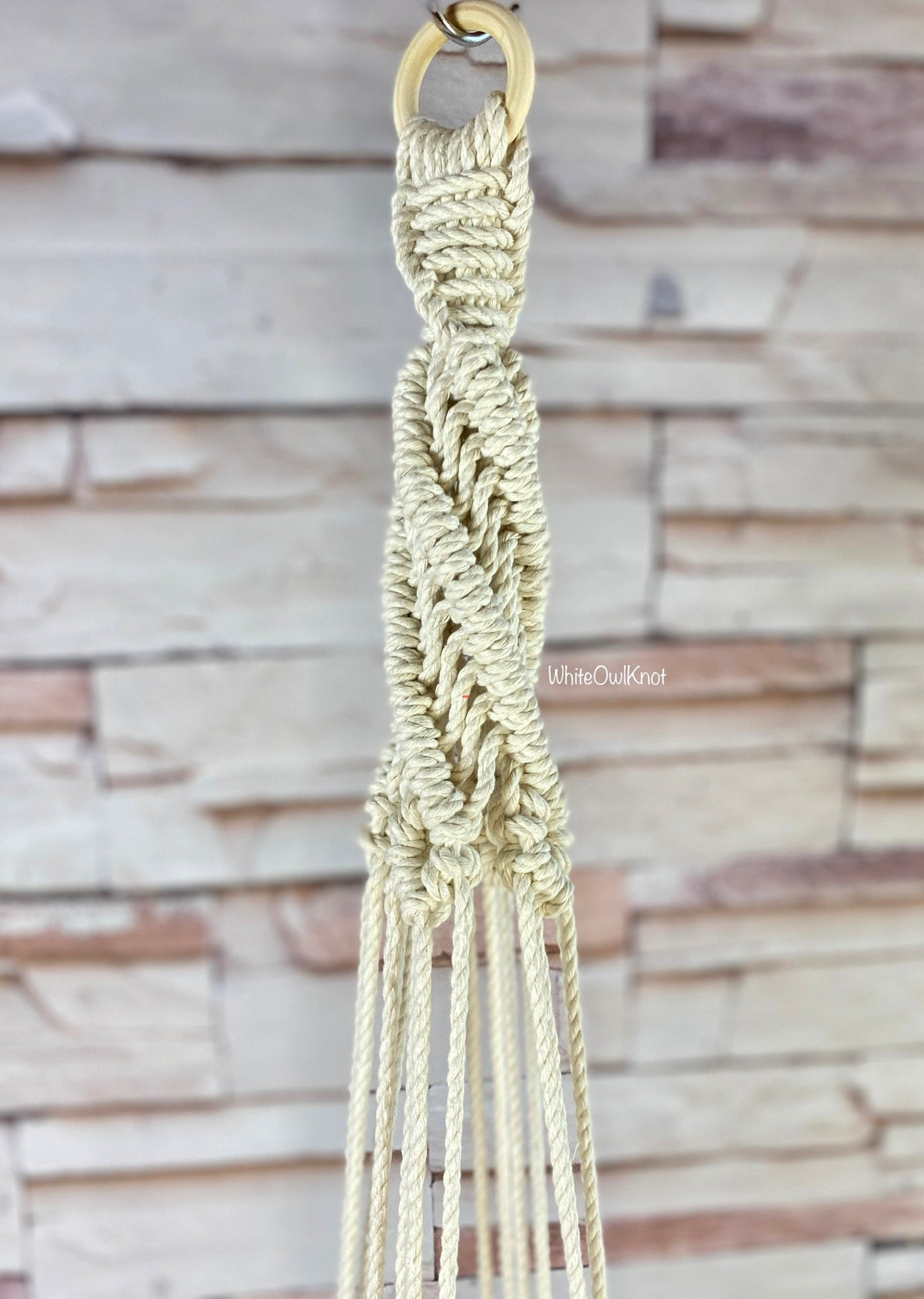 Macrame plant hanger with braided design against a wooden background