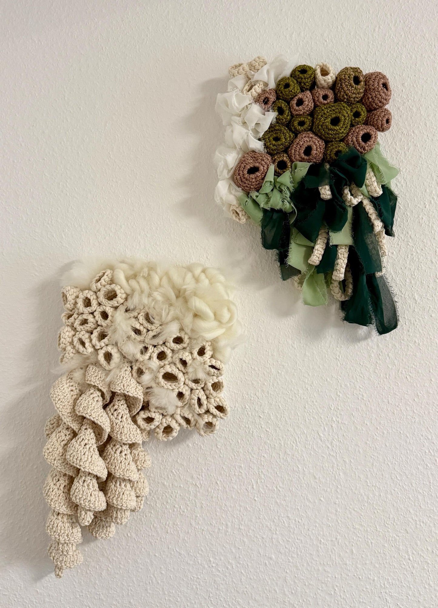 Two crocheted wall hangings on a plain white wall.