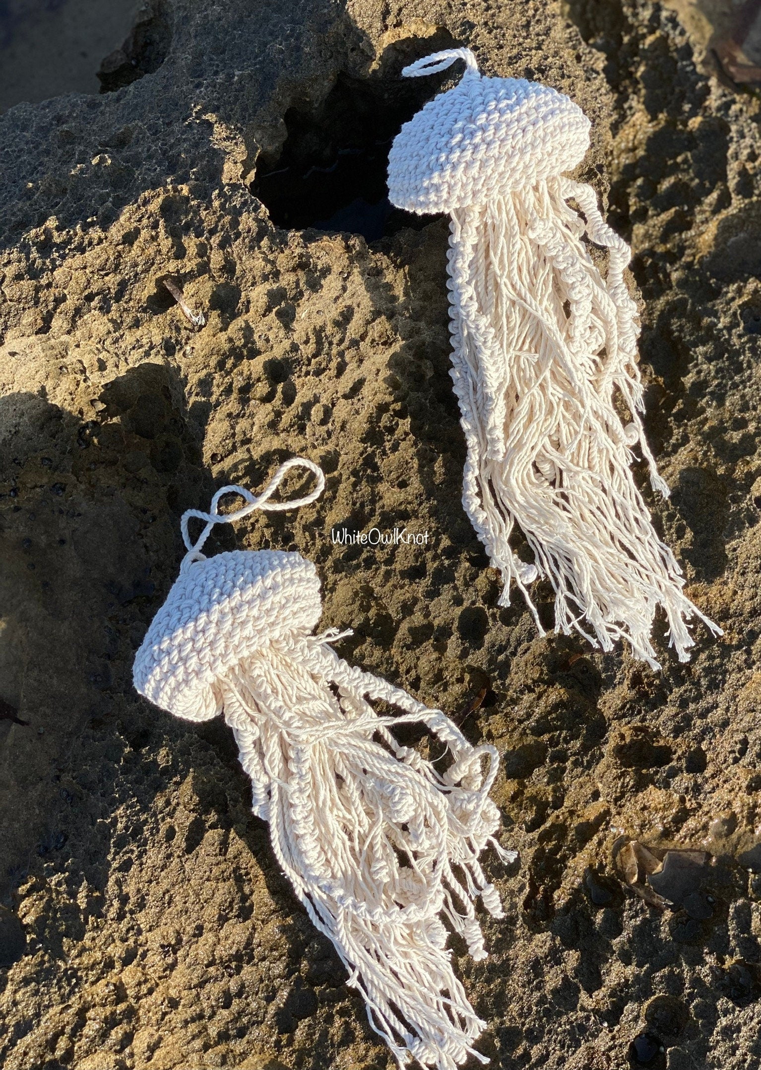Two knotted macrame jellyfish decor on a rocky surface