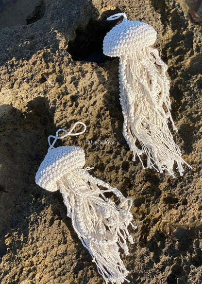 Two knotted macrame jellyfish decor on a rocky surface